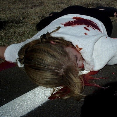 Woman in a blood pool lying on the roadside